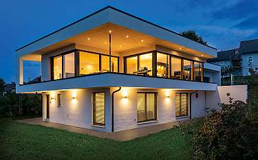 Moderne zweigeschossige Villa mit großen Glasfronten und warmem Innenlicht