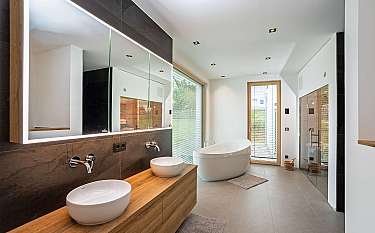 Modernes Badezimmer mit Doppelwaschbecken, freistehender Badewanne und großer Spiegelwand.