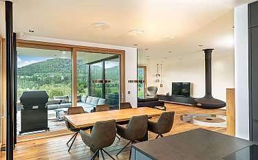 Modernes Esszimmer mit Holztisch, Stühlen und großem Panoramafenster zum Grünen.