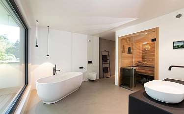 Modernes Badezimmer mit freistehender Badewanne, Waschbecken und integrierter Sauna.