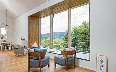Modernes Wohnzimmer mit zwei Sesseln und großem Panoramafenster auf die Landschaft.