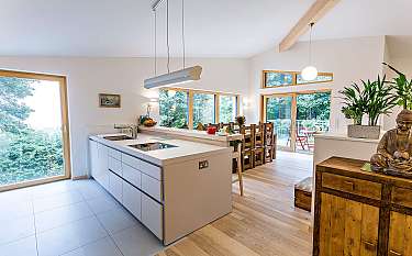 Helle, moderne Küche mit Insel, Holzboden, großen Fenstern und Essbereich.