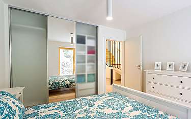 Modernes Schlafzimmer mit gemustertem Bett, Schiebetürschrank und Kommode