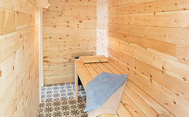 Helle Sauna mit Holzverkleidung, Bank und gemustertem Fliesenboden.