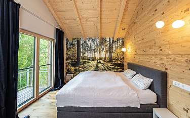 Modernes Schlafzimmer mit Holzwänden, großem Bett und Blick auf einen Balkon.
