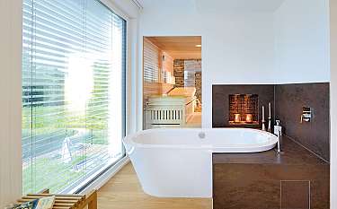 Helles Badezimmer mit freistehender Badewanne, großer Fensterfront und dunkler Duschnische.