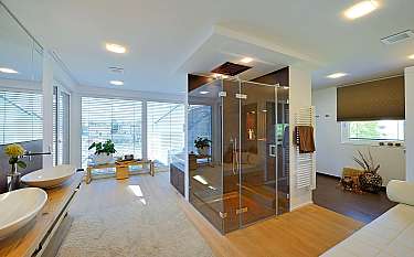 Helles Badezimmer mit Glasdusche, Doppelwaschbecken und großen Fenstern.