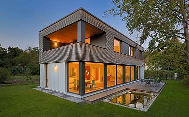 Moderne zweigeschossige Architektur mit großer Glasfront und Terrasse im Garten